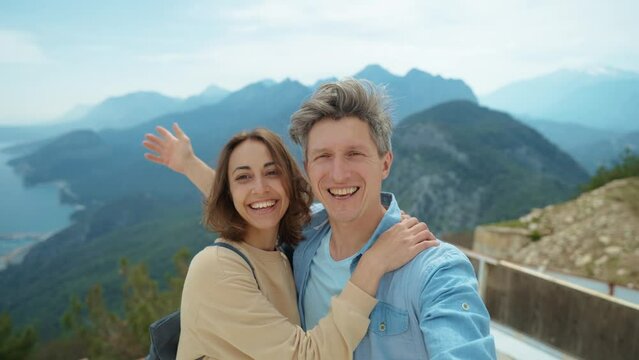 couple happy tourists standing in front of mountain top with cloudy sky at viewpoint of Tunektepe Teleferik, Antalya. man and woman enjoying travel together, taking selfie, hugging and kissing
