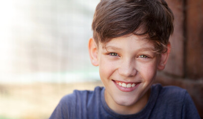 the boy is naturally and liberally smiling at the camera 
