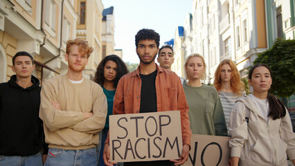Multiracial students on public demonstration at city street against racism with slogans on posters