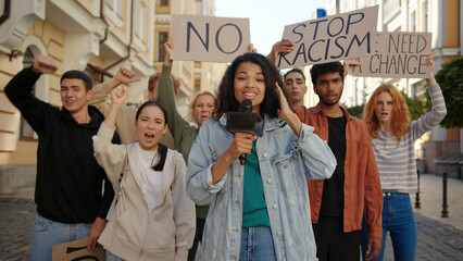 Journalist makes live stream report at camera in front of multiracial protest at city street