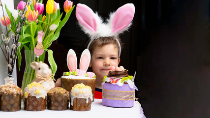 Cute little boy with bunny ears looking at tasty easter sweet cake