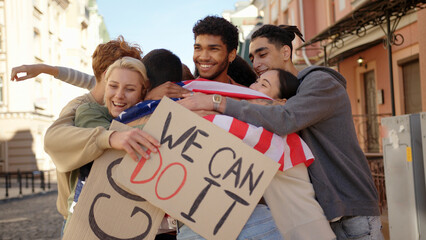 Young protester with USA flag walks to multiracial activists and hugging them. Mass protest concept