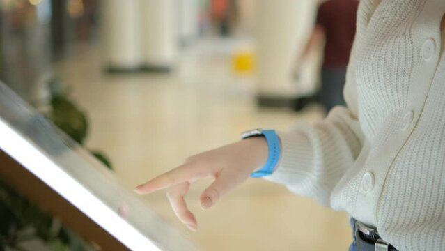 Woman looking for information and store location on digital touch screen in shopping mall 4K