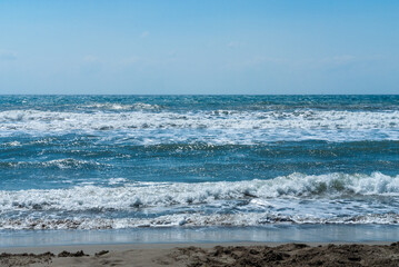 Coast of Mediterranean Sea in Fethiye, Turkey. Turquoise foamy waves run to the sand beach.