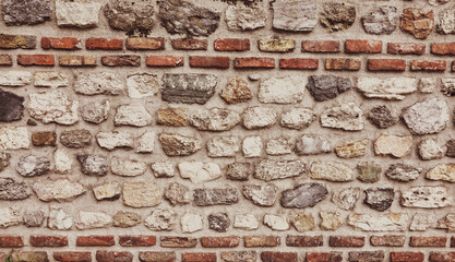 old stone wall background in various colors. The wall of the old historical stone house built with stones one by one