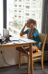 Teenage school boy student wear headphone watch video conference online on laptop. Online education concept.