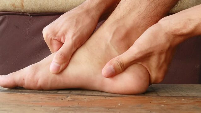 Male is holding his ankle out of pain. System for limbs numbness, paralysis treatment.