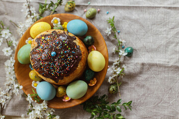 Obraz na płótnie Canvas Happy Easter! Homemade easter bread and natural dyed easter eggs with spring flowers on wooden plate on rustic table. Top view. Traditional Easter food.