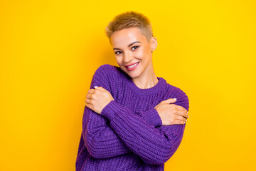 Obraz na płótnie Canvas Photo of girlish smiling blonde short hair lady hug herself wear purple autumn sweater fresh clothes comfort isolated on yellow color background