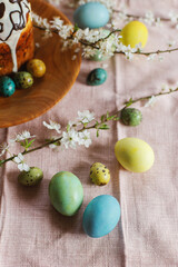 Homemade easter bread and natural dyed easter eggs with spring flowers on wooden plate on rustic table. Top view. Happy Easter! Traditional Easter food.