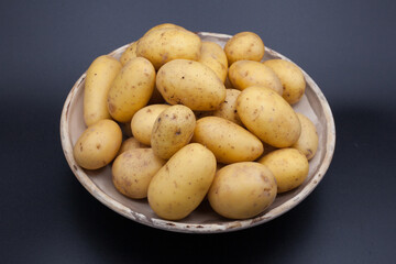 A bowl of new potatoes against a black background