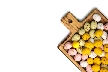 Isolated multi-colored chocolate decorative eggs in wooden tray on a white background. Happy Easter background. Flat lay