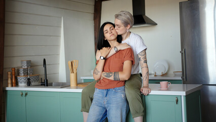 Tattooed lesbian with fair hair and glasses hugs brunette