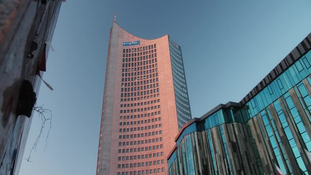 The outside of the university of Leipzig and a skyscraper in Saxony, Germany. The building is a transformed church and showcases modern architecture.  During sunrise golden hour.
