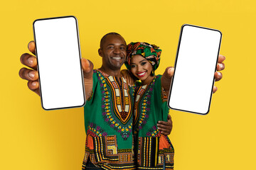 Beautiful loving black couple in traditional costumes showing cell phones