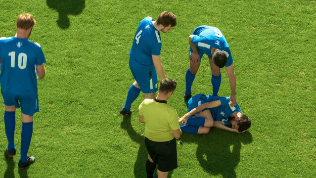 Soccer Football Championship Match: Referee Sees Foul, Gives Signal and Yellow Card, Checks on Injured Player on the Ground. International Tournament. Sport Broadcast Channel Television Concept.