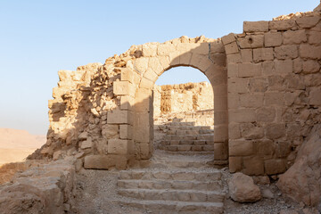 Remains  of a destroyed gate in the rays of the rising sun in the ruins of the fortress of Masada -...