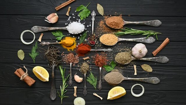 Colorful herbs and spices for cooking. Indian spices. On a black background. Top view