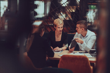 Photo through the glass of a group of business people sitting in a cafe and discussing business plans and ideas for new online commercial services