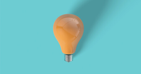 Light bulb in orange color (close up)with reflections against a light blue background. Bulb shadows fall on background