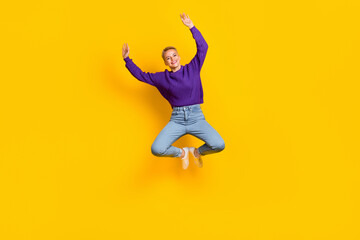 Full size portrait of cheerful overjoyed girl jumping raise hands have fun isolated on yellow color...