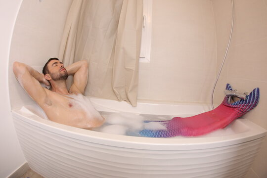 Adult man with merman costume sleeping in the bathtub  