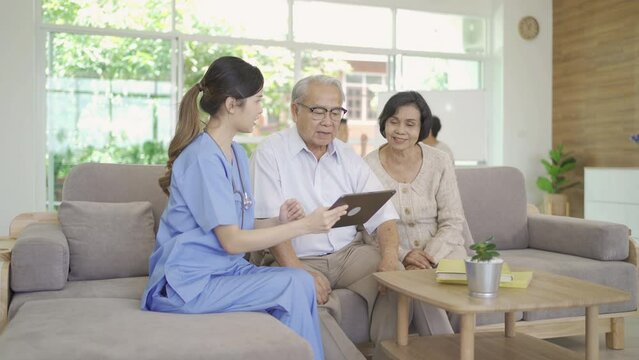 An Asian nurse talking to a group of old elderly patient or pensioner people smiling, relaxing, having fun together in nursing home. Senior lifestyle activity recreation. Retirement. Health care