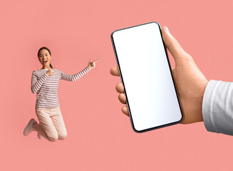Crazy Offer. Excited Asian Female Jumping And Pointing At Big Blank Smartphone