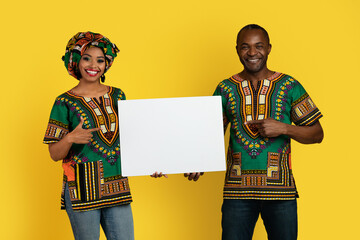 Emotional black couple in traditional costumes showing blank placard