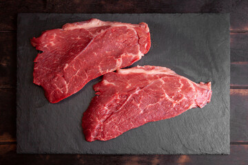 Raw minute steak of marbled beef on a stone slate board