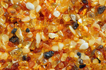 Natural gemstone amber texture background, small stones yellow orange gradient color. Natural mineral material for jewelry. Top view Amber texture. Aesthetic wallpaper, pieces ancient resin.