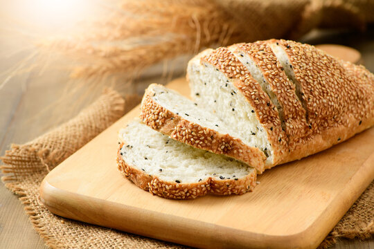sliced french grain breads with white and black sesame on wood background
