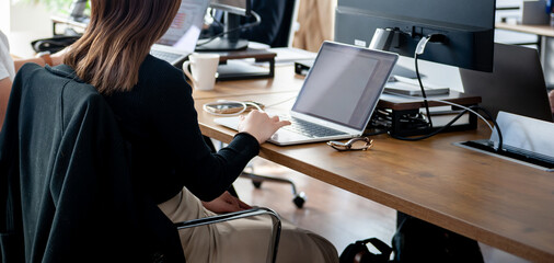 オフィスでのビジネスシーン、IT企業、ノートパソコンのキーボードを打つ女性　