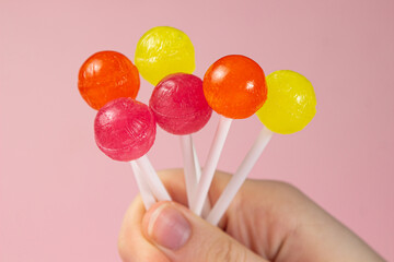 Female hand holding different lollipops on a pink background