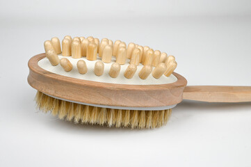 Wooden brush on a background. Home body care. Brush for anti-cellulite massage. Massage brush for the body.