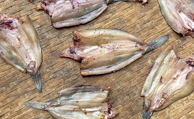 Sun dried snakehead fish on a woven bamboo tray.