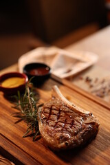 a steak is sitting on a wooden table with a bowl of sauce next to it and a napkin