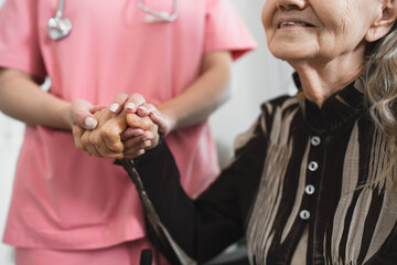 Hand holding caucasian older woman and doctor or nurse at home 