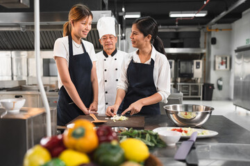 Happy student Asia woman assistant chef learning cooking of Asia senior chef and kitchen background