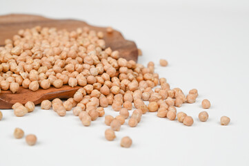 Scattered chickpea in a wooden plate, isolated on white backround