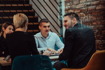Happy businesspeople smiling cheerfully during a meeting in a coffee shop. Group of successful business professionals working as a team in a multicultural workplace.