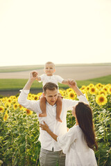 Mother, father and son in white clothes at the sunflowers field