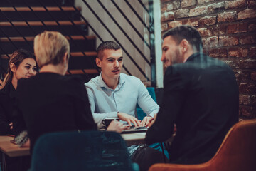 Obraz premium Happy businesspeople smiling cheerfully during a meeting in a coffee shop. Group of successful business professionals working as a team in a multicultural workplace.