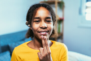 Beautiful smiling black deaf girl using sign language at home © Mediteraneo