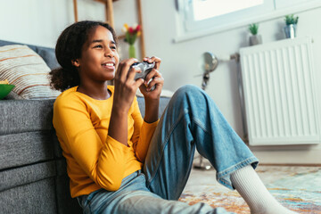 Young African American little girl at home playing video games