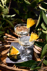 Champagne cocktail with pineapple decoration on a rattan table