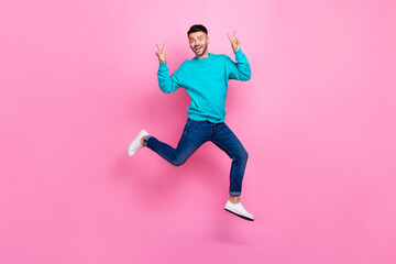 Fototapeta na wymiar Full body photo of young nice guy jumping excited showing double v-sign dressed stylish blue clothes isolated on pink color background