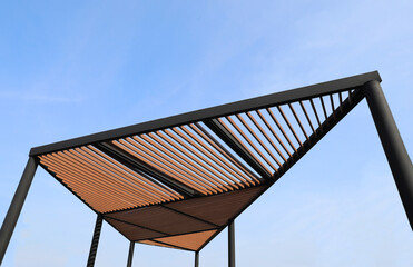 Wooden slats roof with blue sky background. Wooden slat shading structure.