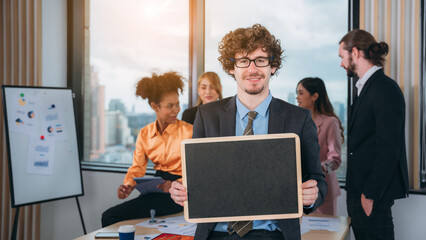 Portrait of happy Business holding Blank chalkboard and people converse during a meeting about papers and concepts.