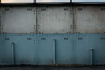 Large concrete fence. The upper half is gray, the lower half is blue. Three ventilation pipes.